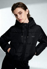 Woman posing with hands in pockets while wearing Vans VN0A4B8MBLK1 black puffer bomber jacket.