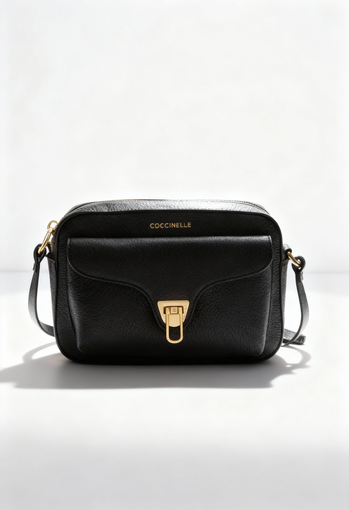 Coccinelle black leather across-body bag, front view showing turn-lock logo and smooth leather.