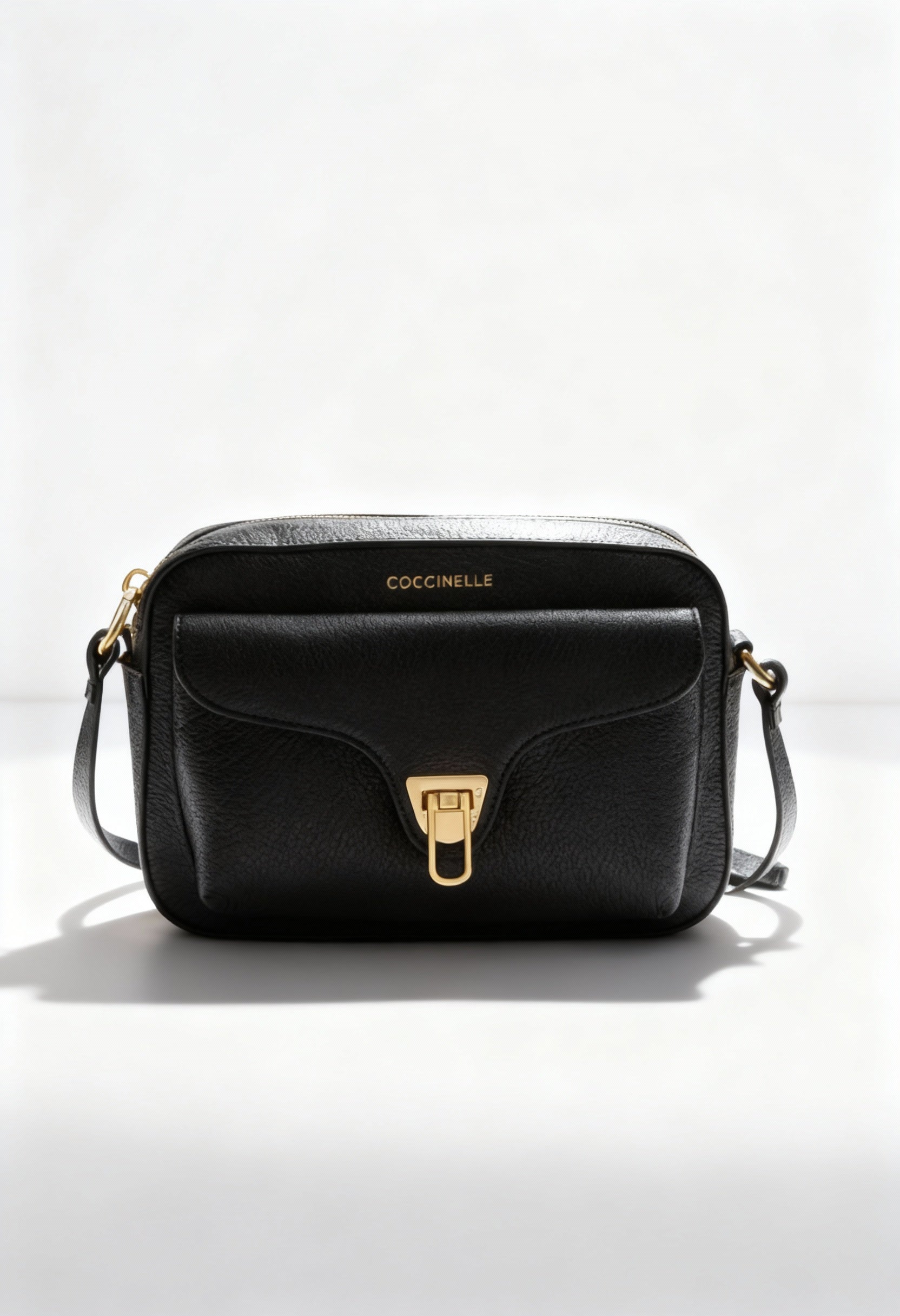 Coccinelle black leather across-body bag, front view showing turn-lock logo and smooth leather.