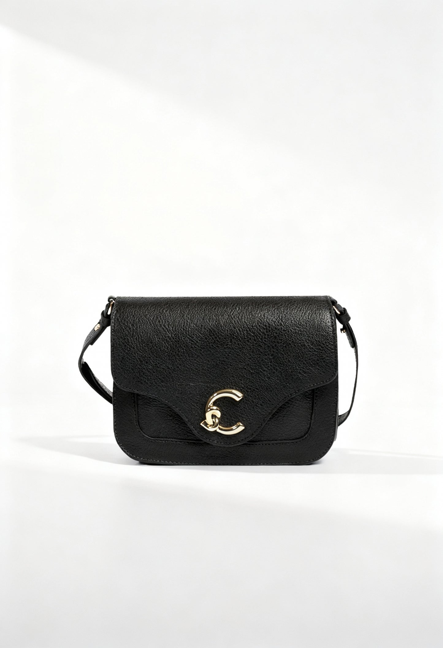 Coccinelle black leather across-body bag, front view showing C-clasp and textured leather.