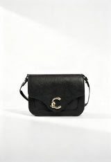 Coccinelle black leather across-body bag, front view showing C-clasp and textured leather.