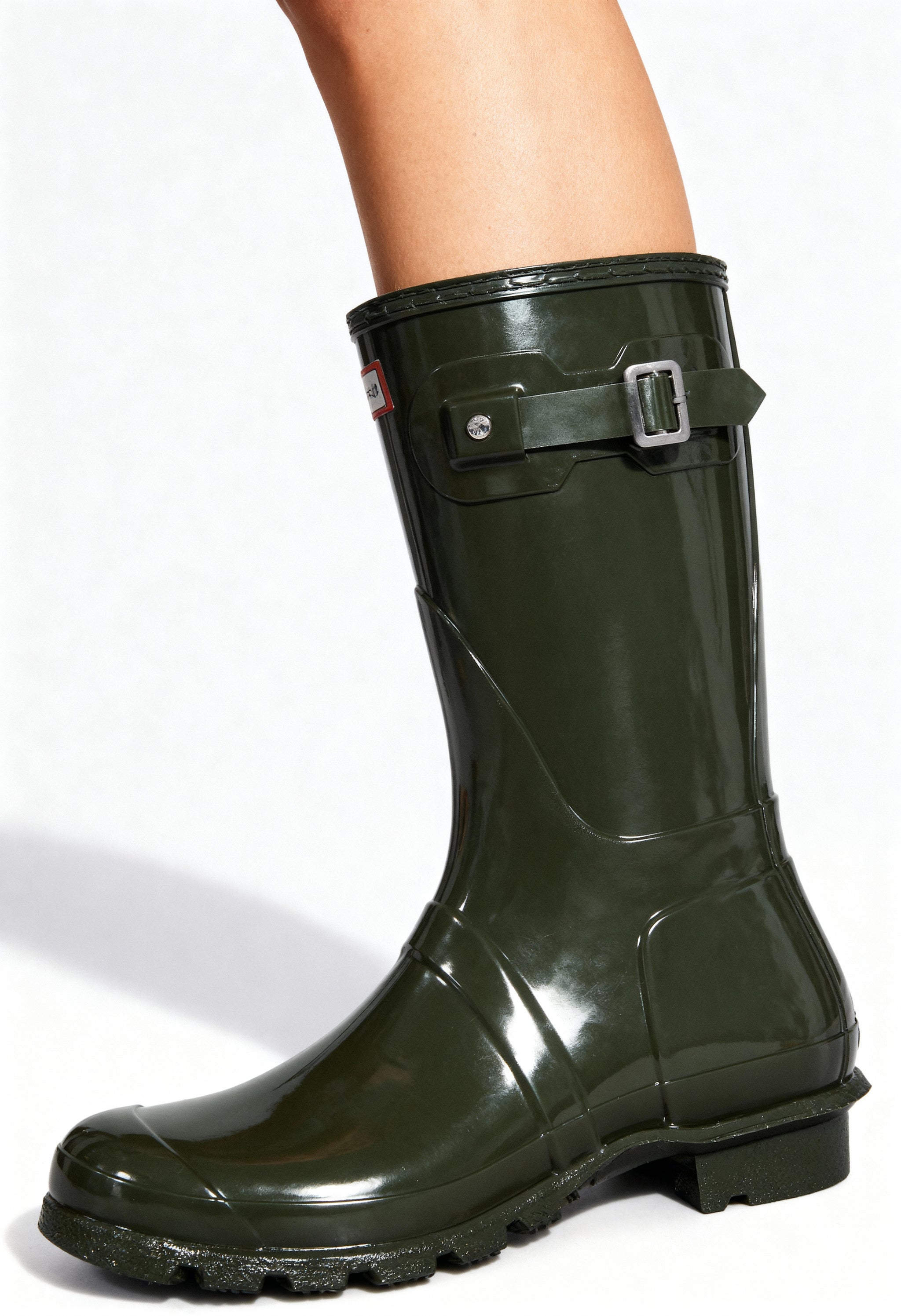 On-foot view of the dark green Hunter gloss rain boots with buckle detail and round toe.