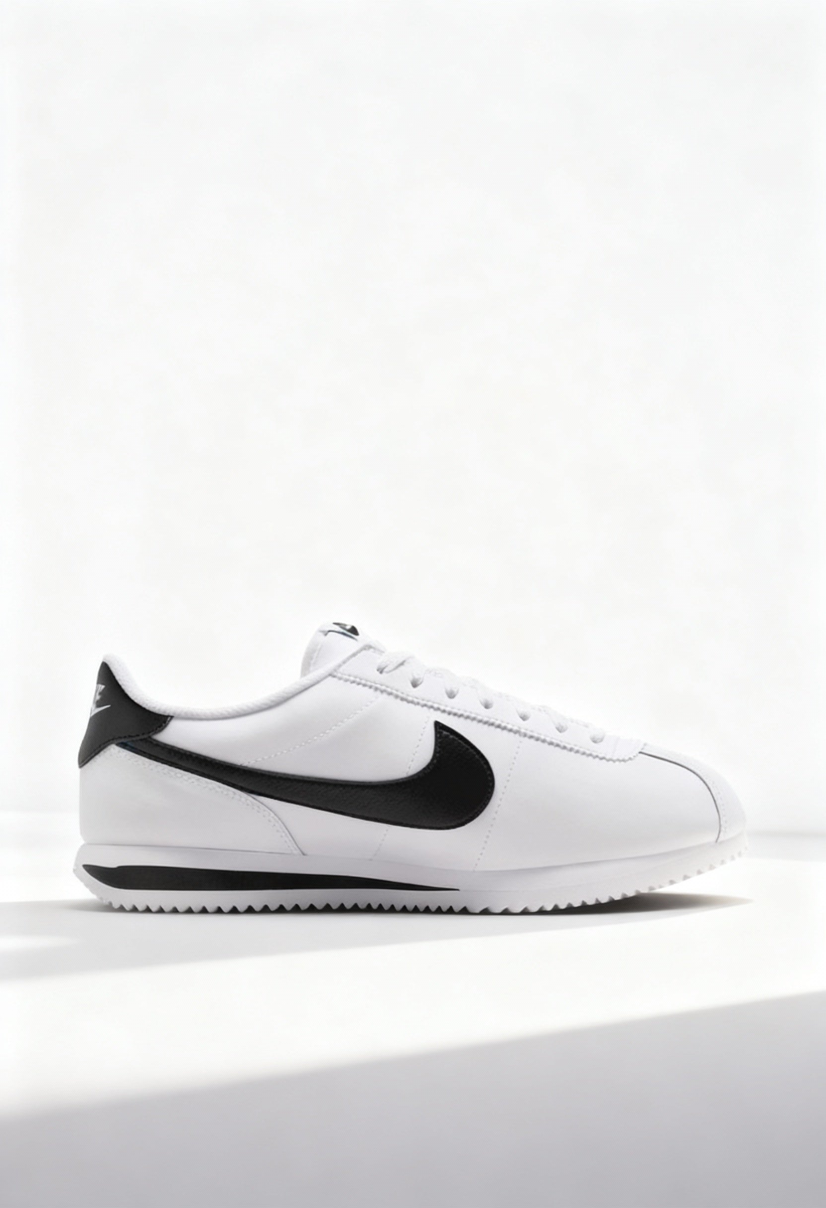 Brand new Nike Cortez men's sneakers in white leather with black Swoosh side view.