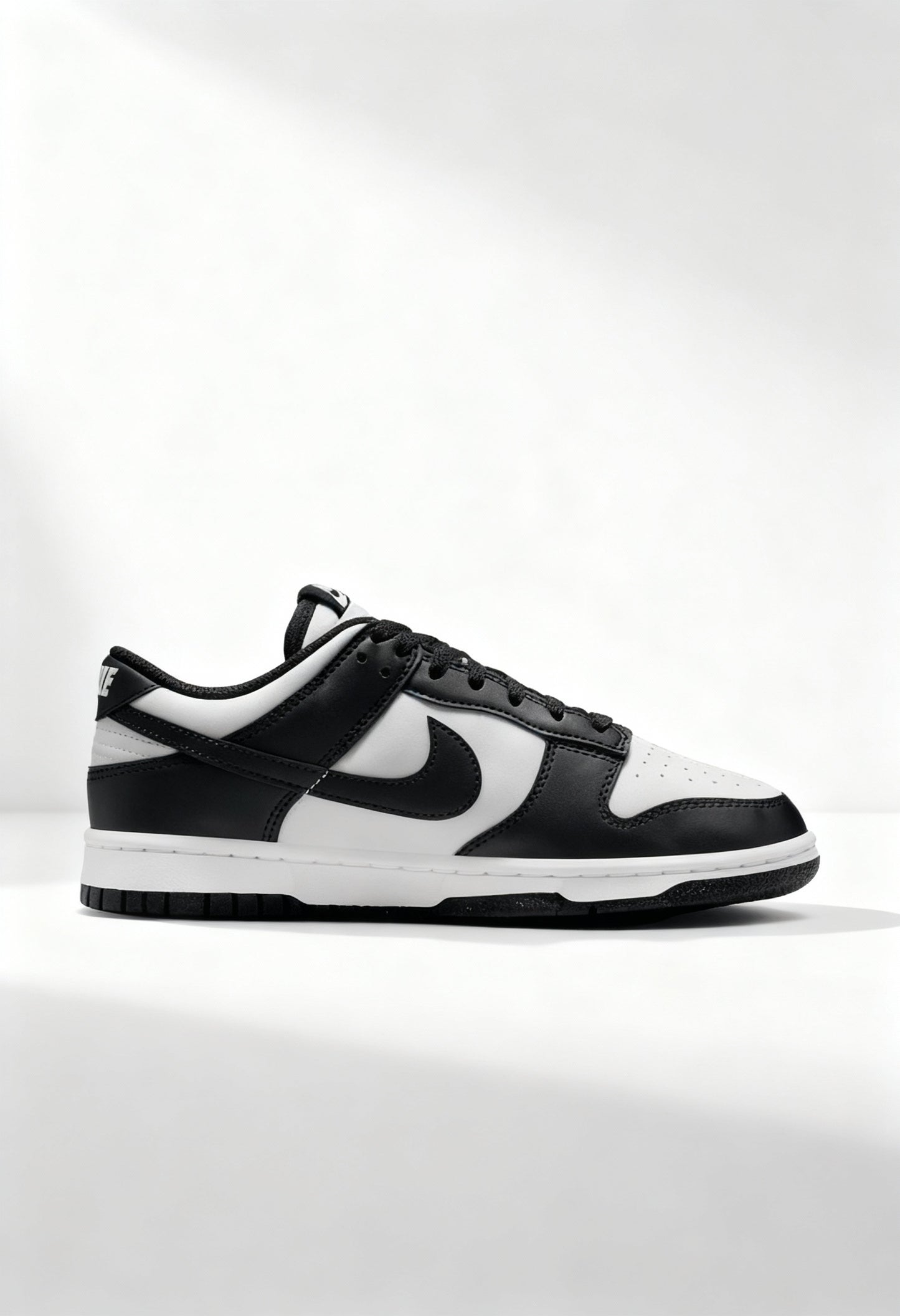 Brand new Nike Dunk Low Next Nature women's sneakers in black and white side view.